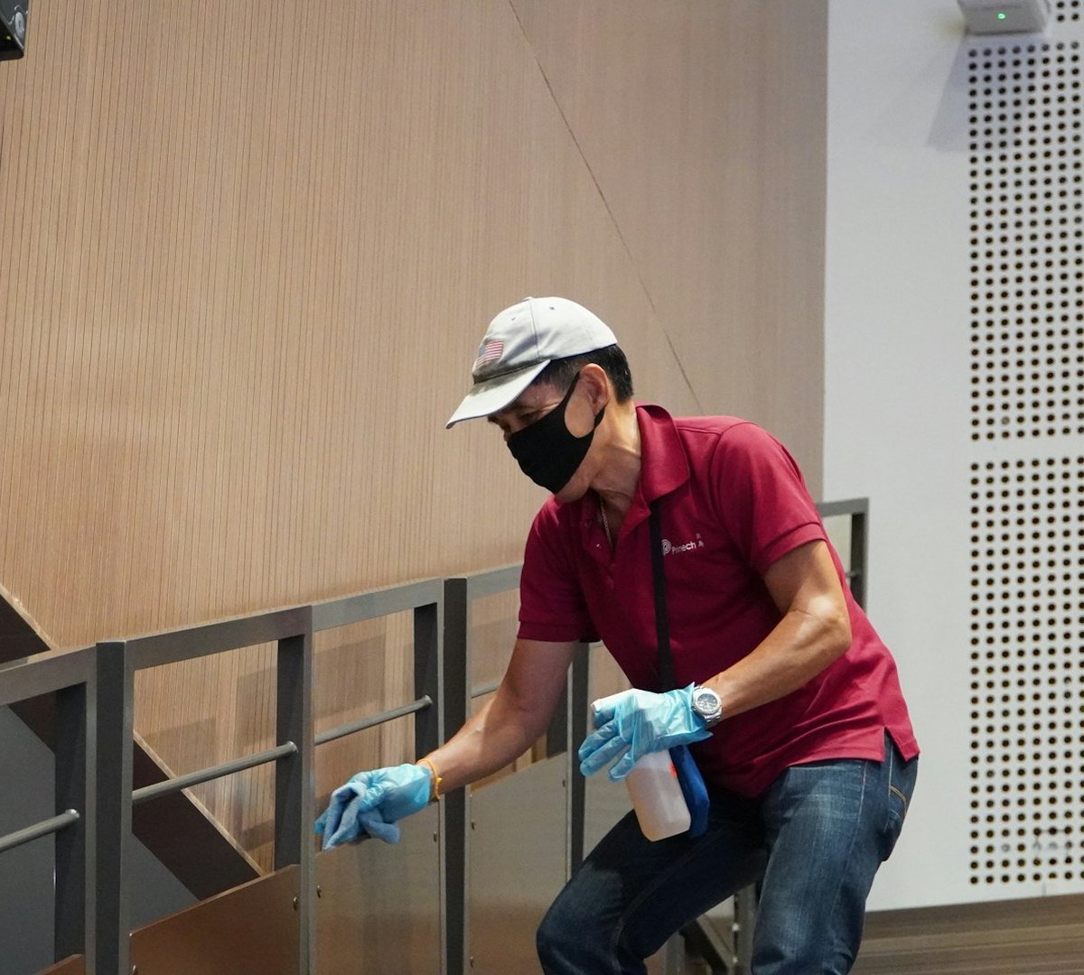 Cleaner wiping down a handrail in a building common area
